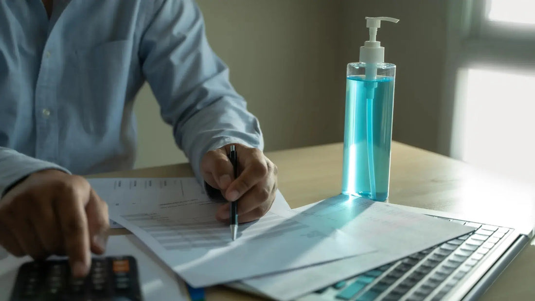 Person reviewing cosmetic compliance documents beside a laptop and product sample during cosmetic product safety documentation.